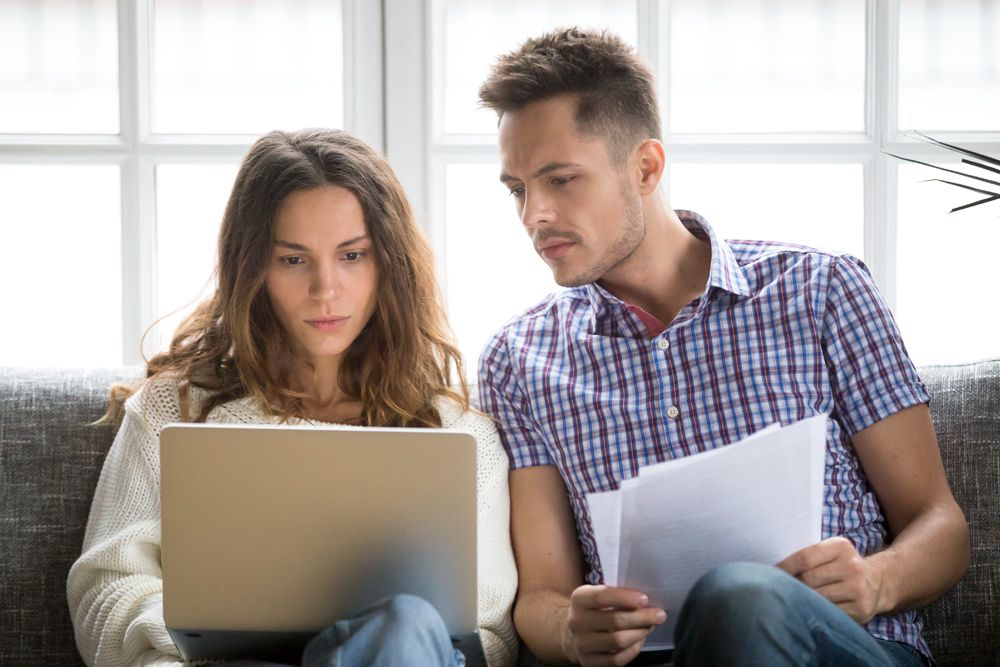 Couple on couch researching on laptop